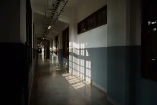 Ilustrasi: Lorong panjang sebuah gedung kosong dengan bayangan cahaya jendela di dinding dan lantai.