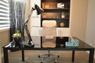 Ilustrasi: Ruang kerja rapi dengan meja hitam, kursi kantor, dan lampu meja.