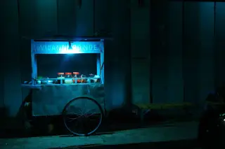 Ilustrasi: Gerobak jualan wedang ronde di pinggir jalan pada malam hari dengan penerangan lampu.