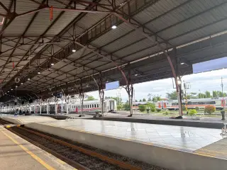 Ilustrasi: Peron stasiun kereta api di Indonesia dengan gerbong kereta yang terparkir di jalur rel.