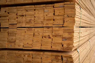 Ilustrasi: Tumpukan papan kayu yang tersusun rapi untuk keperluan konstruksi.
