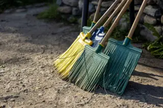 Ilustrasi: Beberapa sapu plastik bersandar di dekat tumpukan batu di luar ruangan.