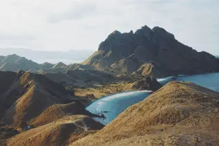 Ilustrasi: Pemandangan lanskap perbukitan gersang dan pantai berpasir putih di Pulau Padar.