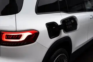 Ilustrasi: Tampak dekat bagian belakang mobil listrik putih dengan soket pengisian daya yang terbuka.
