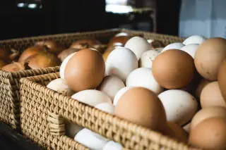 Ilustrasi: Tumpukan telur ayam dan bawang dalam keranjang anyaman rotan.