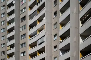 Ilustrasi: Fasad bangunan gedung apartemen bertingkat dengan deretan balkon beton.