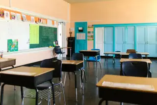 Ilustrasi: Ruang kelas kosong dengan deretan meja dan kursi sekolah tanpa murid.