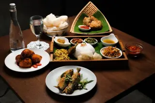 Ilustrasi: Aneka hidangan masakan tradisional dengan nasi dan lauk tersaji di atas meja kayu.
