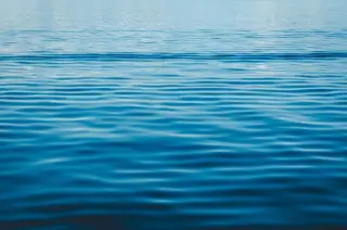 Ilustrasi: Permukaan air laut berwarna biru dengan riak-riak gelombang kecil.