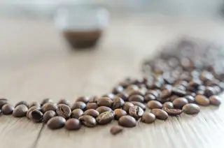 Ilustrasi: Biji kopi sangrai berserakan di atas meja kayu dengan latar belakang buram.