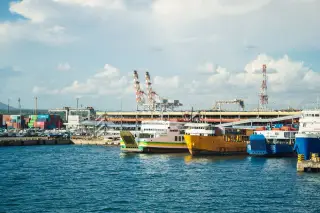 Ilustrasi: Sejumlah kapal feri bersandar di dermaga pelabuhan dengan latar peti kemas dan derek industri.