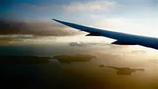 Ilustrasi: Pemandangan sayap pesawat terbang di atas pulau-pulau dan lautan saat senja.