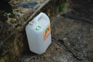 Ilustrasi: Sebuah jeriken plastik putih diletakkan di atas lantai batu di luar ruangan.