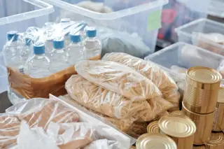 Ilustrasi: Paket botol air mineral, makanan kering, dan kaleng tersusun di dalam wadah penyimpanan.