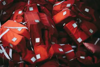 Ilustrasi: Tumpukan pelampung keselamatan berwarna merah dengan tali putih.