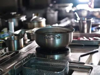 Ilustrasi: Panci dan peralatan masak berbahan baja tahan karat di atas kompor dapur komersial.