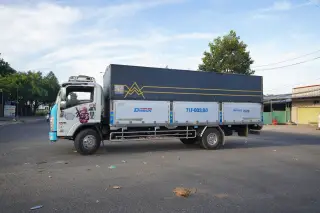 Ilustrasi: Sebuah truk kargo berpenutup terpal terparkir di pinggir jalan beraspal.