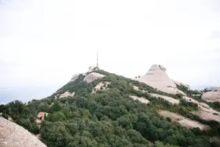 Ilustrasi: Menara komunikasi berdiri di atas bukit berbatu dan rimbun pepohonan.