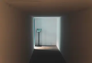 Ilustrasi: Lorong sempit dan sepi dengan papan petunjuk kecil di ujung yang diterangi cahaya.