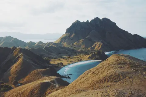 Ilustrasi: Pemandangan lanskap perbukitan gersang dan pantai berpasir putih di Pulau Padar.