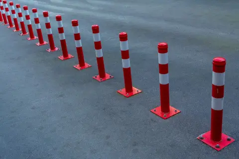 Ilustrasi: Deretan tiang pembatas jalan berwarna merah putih di atas permukaan aspal.